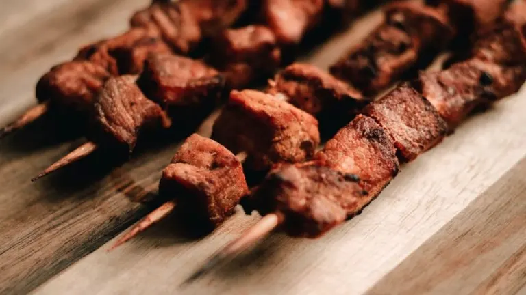 Close-up view of grilled meat skewers on a wooden board, perfect for BBQ-themed visuals.