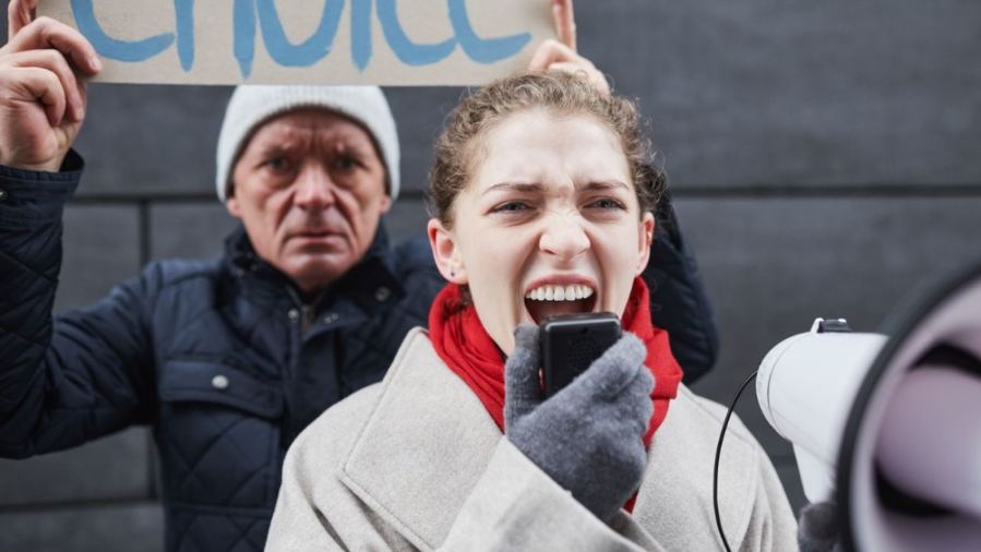 Two protestors at a rally, one speaking passionately into a megaphone, conveying strong messages.