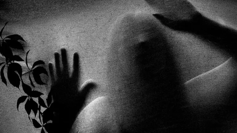 Mysterious figure with hands pressed against frosted glass, evoking a spooky atmosphere.