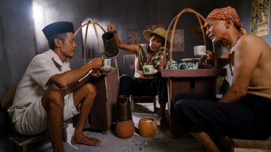 Men enjoying a social coffee break in a traditional Indonesian setting.