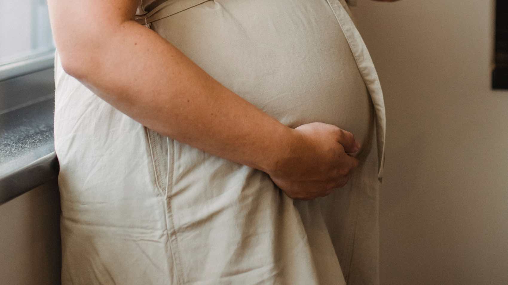Cheerful pregnant woman enjoying leisure time at home with smartphone.