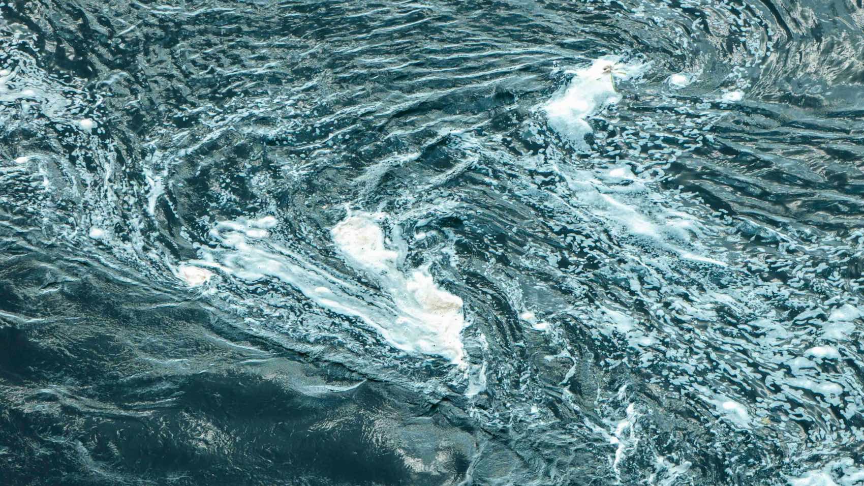 A mesmerizing aerial view of swirling ocean water patterns with whitecaps.