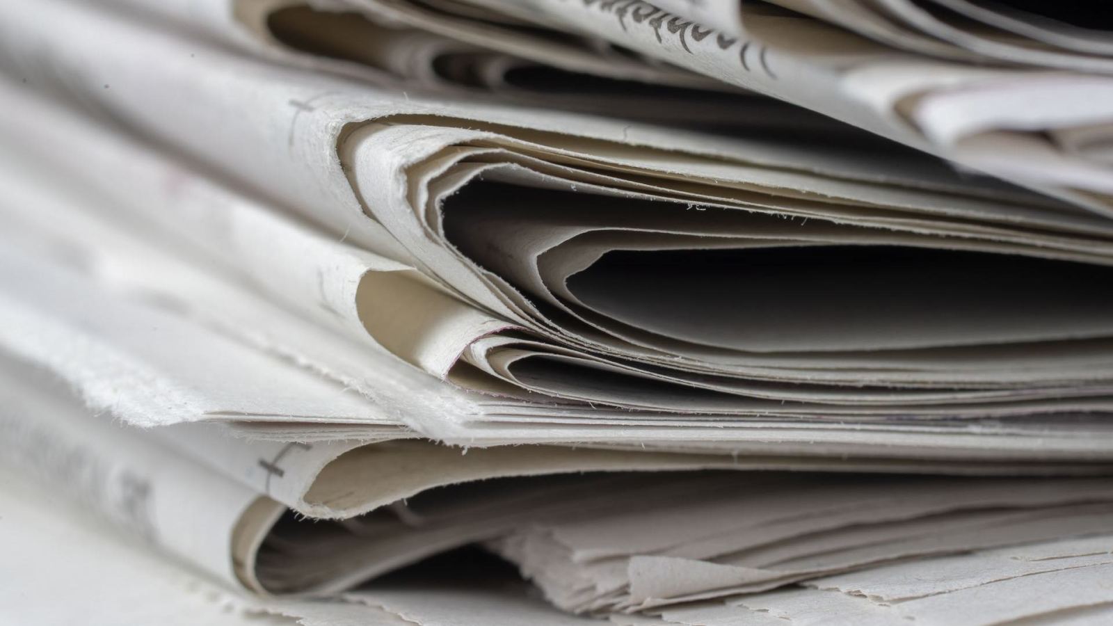 A detailed close-up view of stacked newspapers, highlighting textures and layers.