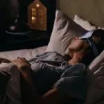 A woman peacefully sleeping with an eye mask in a dimly lit bedroom, capturing a serene bedtime atmosphere.