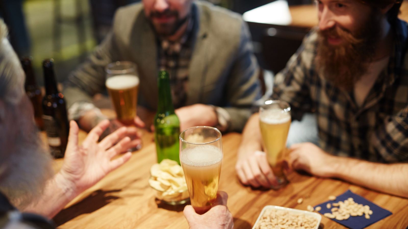 A group of men enjoying drinks, snacks, and conversation at a pub table.
