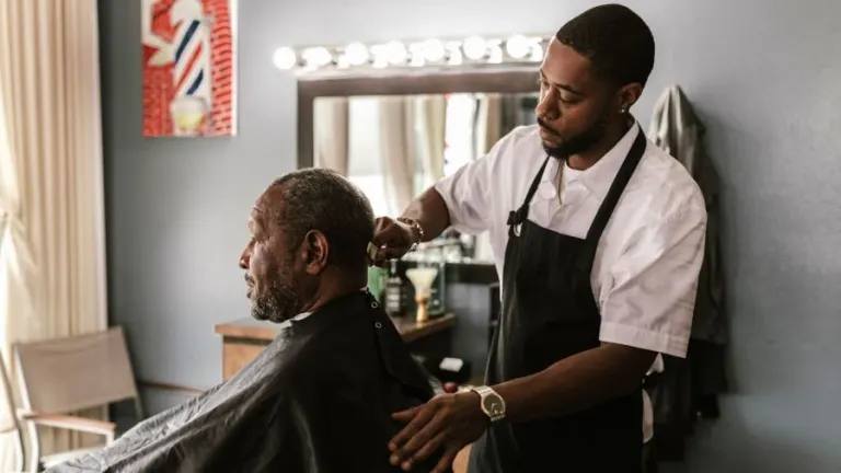 A barber meticulously trims a customer's hair in a stylish barbershop setting.