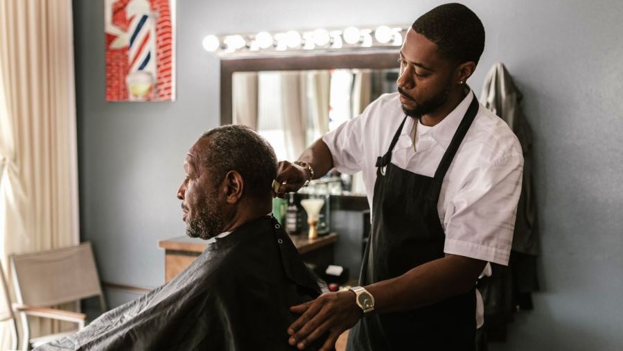 A barber meticulously trims a customer's hair in a stylish barbershop setting.