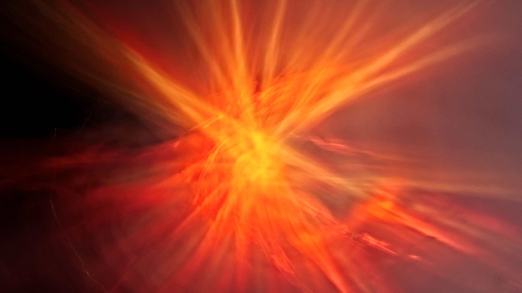 Dynamic explosion of red orange rays in an abstract art form, vibrant and energetic.