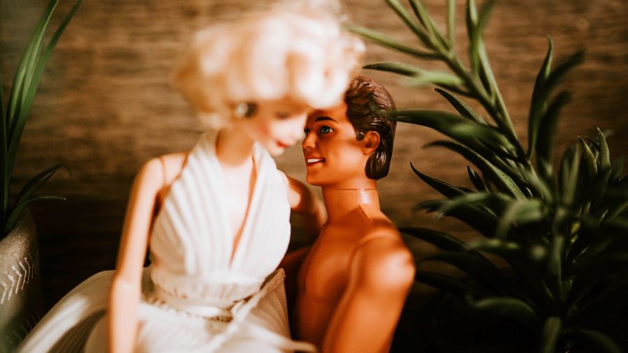 Romantic scene with dolls embracing, surrounded by indoor plants.