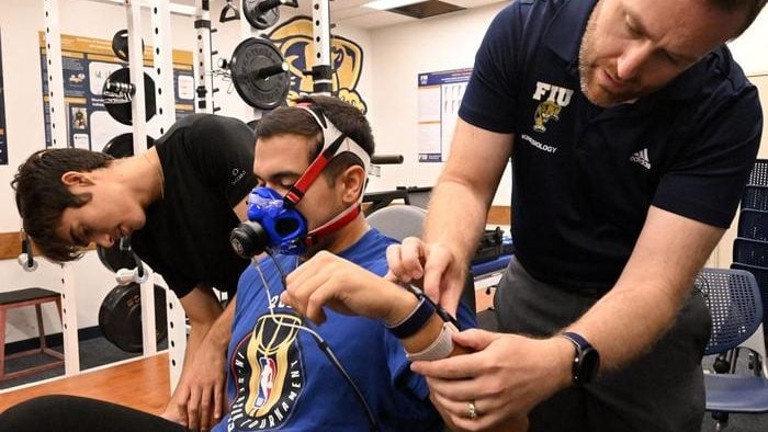 From left, bachelor's student Gabriel Cabeda Ramirez, Ph.D. student Daimien Campos and FIU professor Jason Kostrna review readings from four smartwatches worn by Campos as he rides a stationary bike. Their study evaluated how accurately popular smartwatches estimate calories burned during exercise. CREDIT Photo by Taimy Alvarez/Florida International University