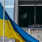 Ukrainian flag waving in front of a damaged building in Kyiv, Ukraine.