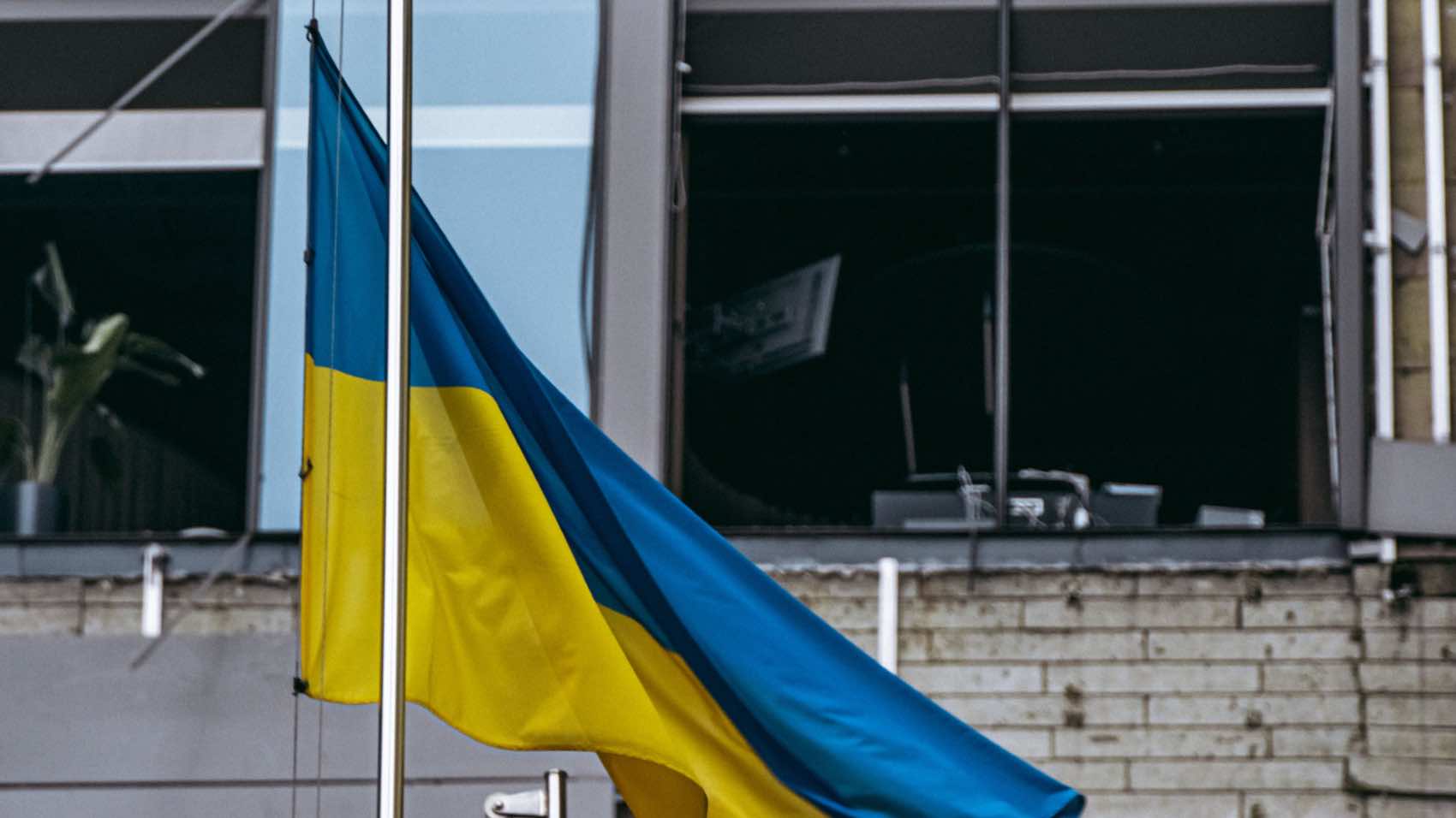 Ukrainian flag waving in front of a damaged building in Kyiv, Ukraine.