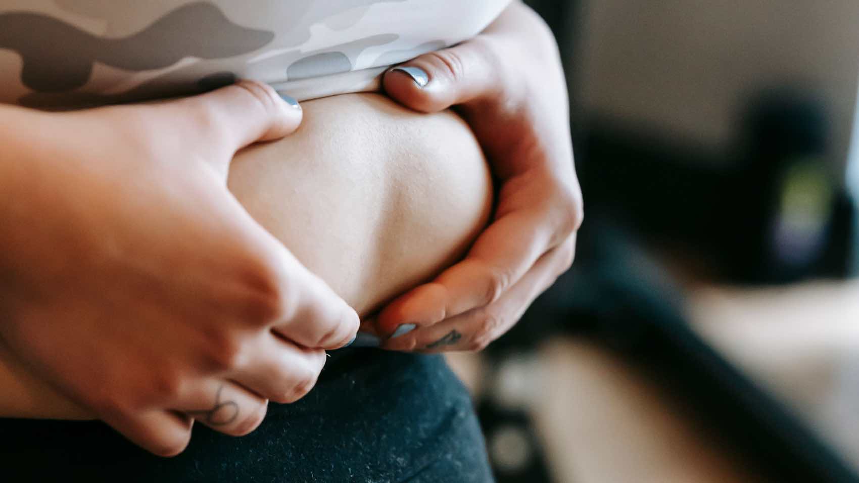 A woman in activewear holding her belly, emphasizing fitness and wellness.