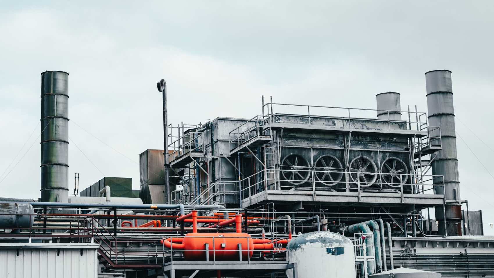 A modern industrial facility featuring complex machinery and infrastructure under a cloudy sky.