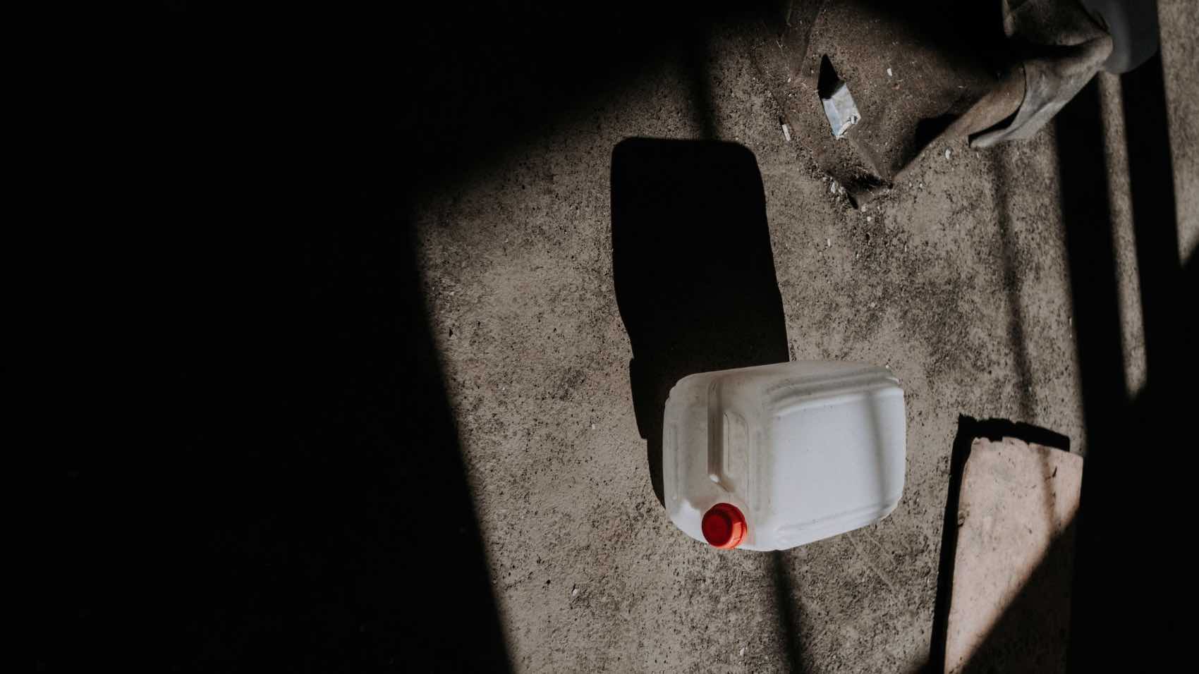 A solitary plastic canister rests on the floor, bathed in dramatic shadows.