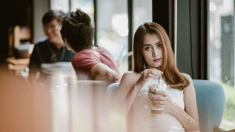 Young woman in a white dress relaxing with a cold drink in a modern cafe.