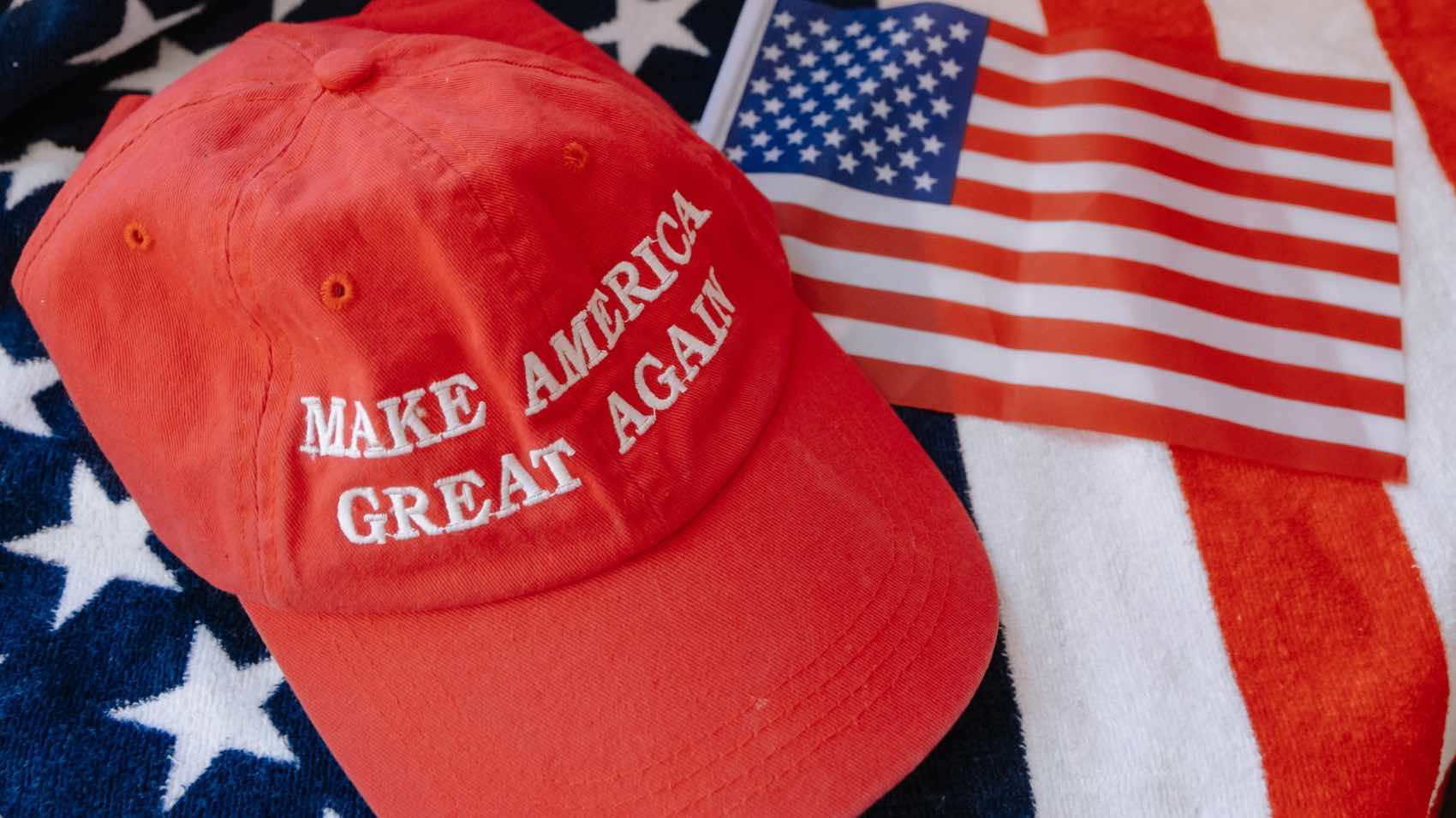 Red cap with 'Make America Great Again' text on US flag background.