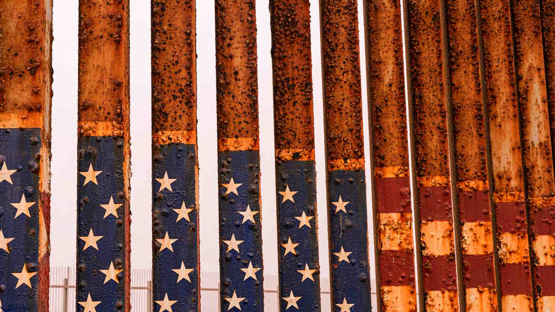 Close-up of a rusty iron fence painted with stars and stripes at the American-Mexican border in Tijuana.