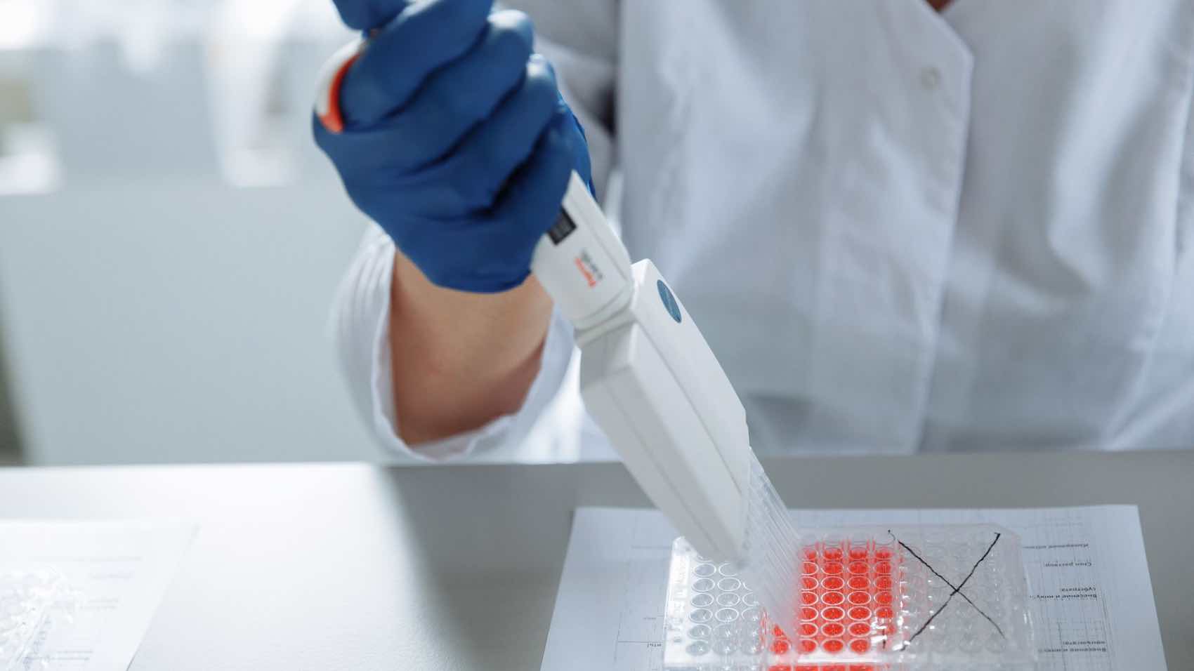 Close-up of a scientist using a pipette in a lab with a focus on sterile procedures.