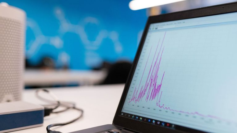Laptop displaying data analytics graph in a modern office setting, symbolizing growth and technology.