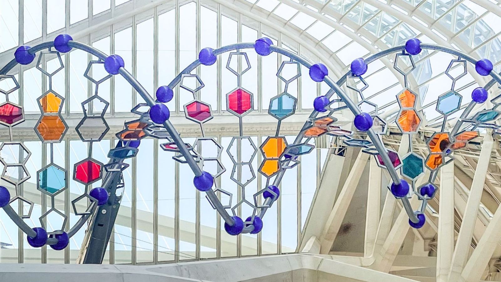 Colorful DNA sculpture inside Valencia's science complex, showcasing modern architecture and art.