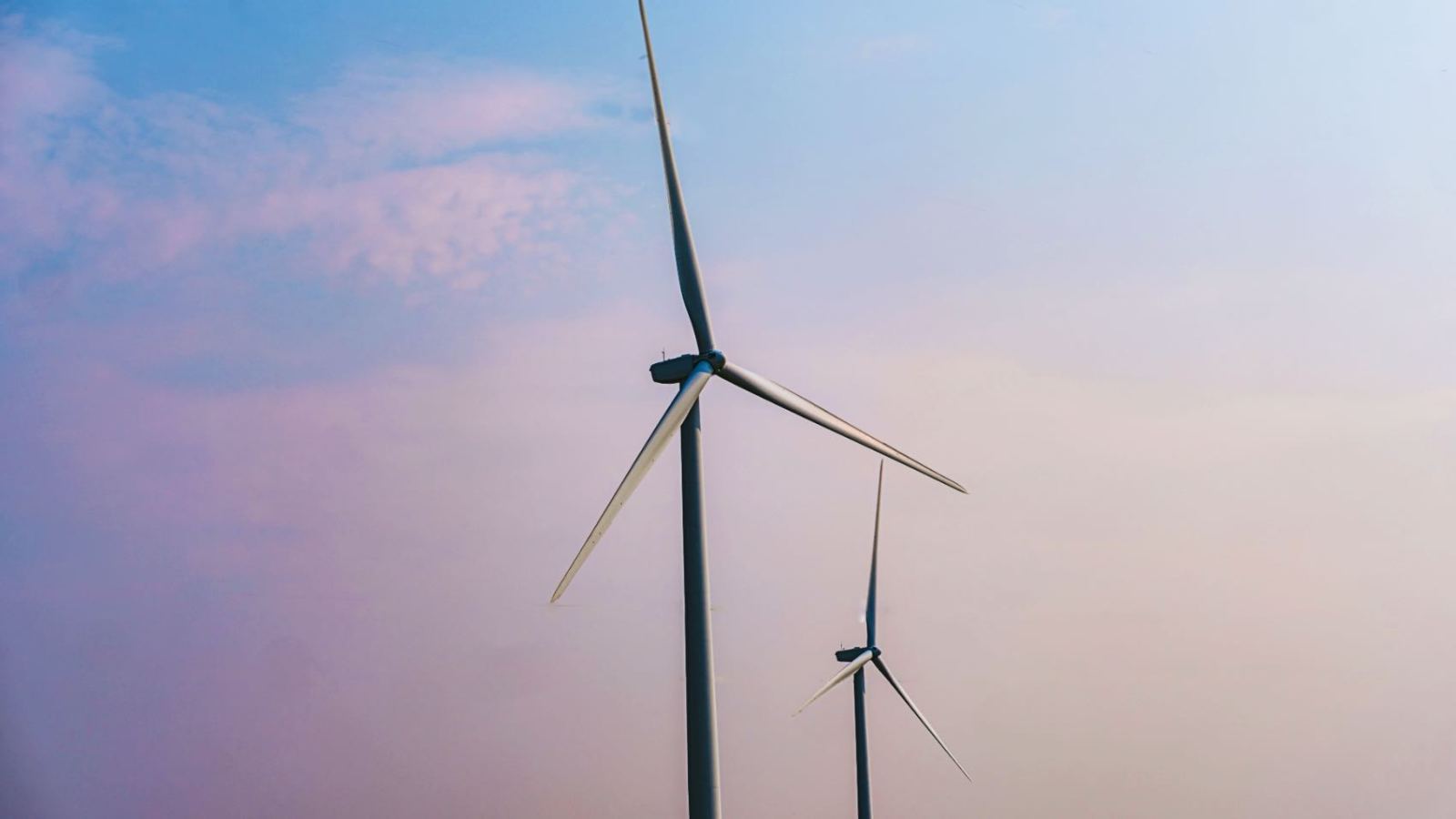 Two wind turbines stand tall under a clear sky, emphasizing renewable energy solutions.